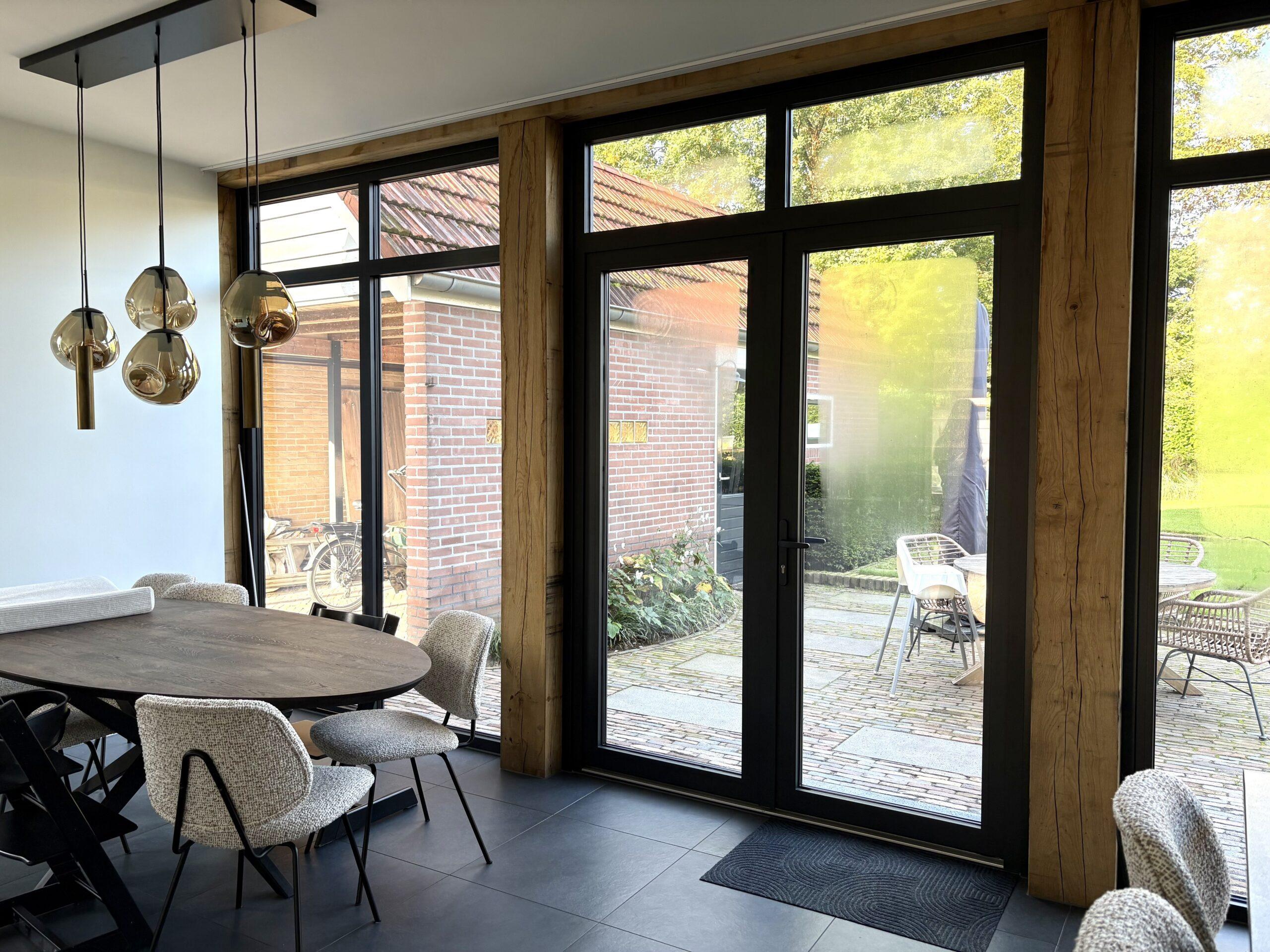 Eetkamer in de uitbreiding met eiken staanders en aluminium tuindeuren